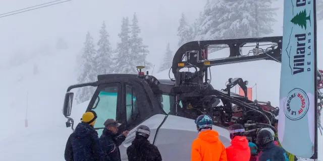 Véhicule tout-terrain orange et bleu d’une équipe de secours en montagne, avec des personnes en combinaison de protection et des équipements médicaux