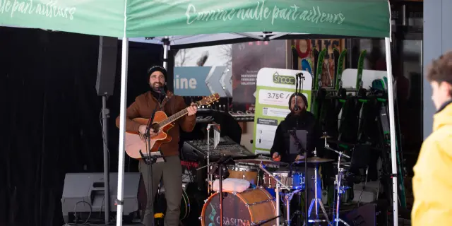Deux musiciens jouant de la guitare et de la batterie sous une tente de marché de nuit