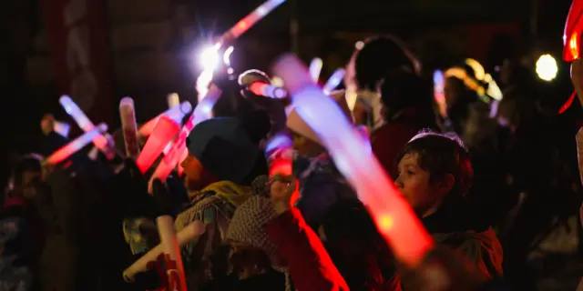 Groupe de personnes célébrant avec des lumières colorées sur un port