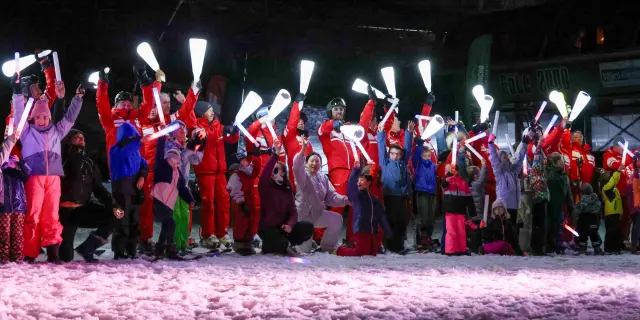 Groupe de danseurs en costumes traditionnels rouges et violets, alignés sur une scène éclairée