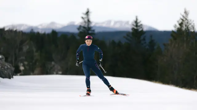 Sciatore in tuta blu e berretto rosso che scende una pista innevata