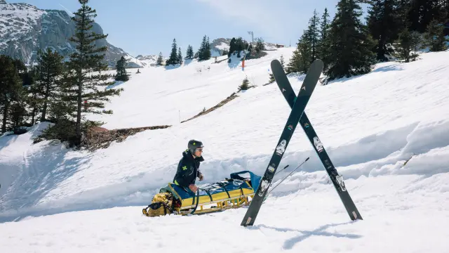 Bambino in abbigliamento da sci che trascina una slitta con un cane su una pista innevata