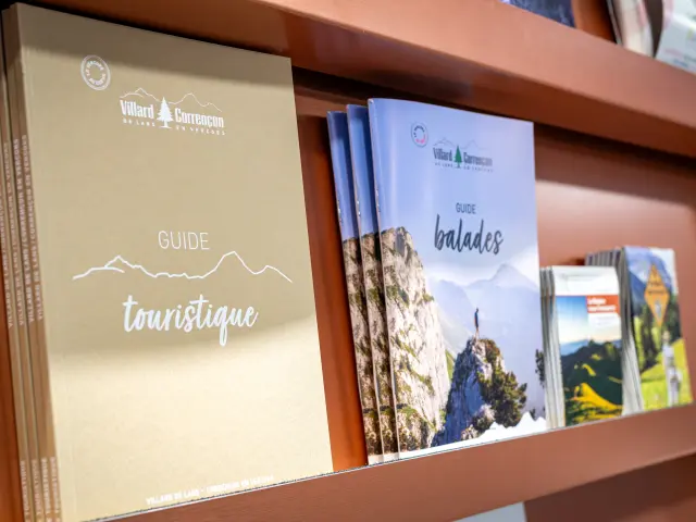 Two open tourist guides in a wooden display case, showing maps and landscape illustrations