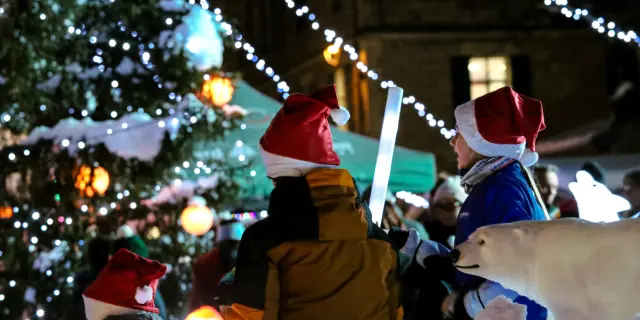 Christmas market stalls lit by string lights, with visitors around