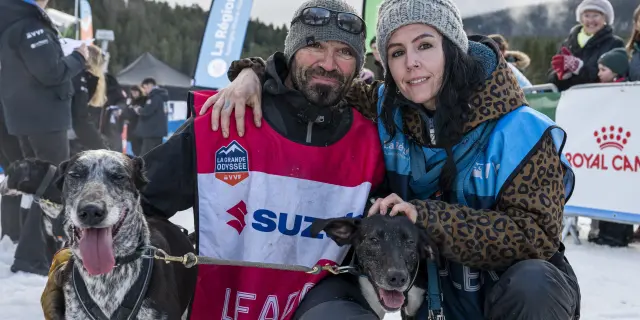 Deux personnes tenant des pancartes 'LEAP' et 'SUZUKI' lors d'un événement sportif avec des chiens en laisse