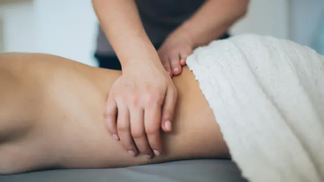 Pieds d’une personne allongée sur une table de massage avec des pierres chaudes posées sur les chevilles