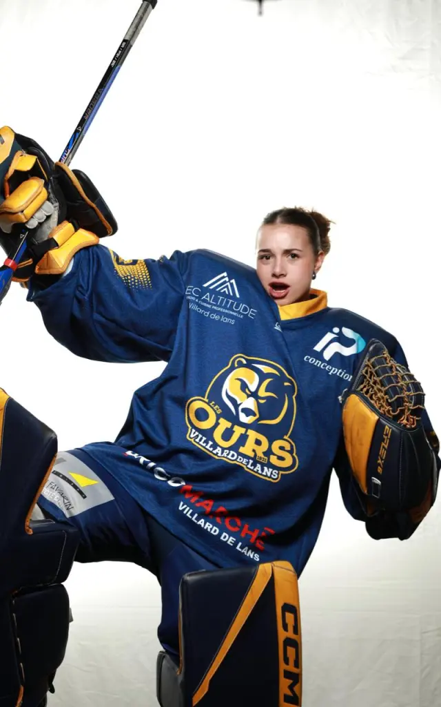 Joueur de hockey en tenue bleue célébrant avec une crosse levée