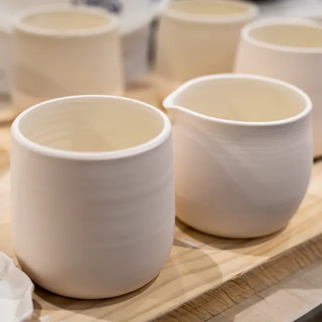Deux bols en céramique blanche contenant un liquide doré, posés sur une table en bois