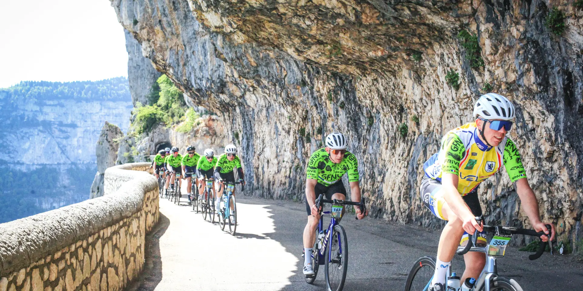 Due ciclisti in tenuta da competizione percorrono una strada di montagna al tramonto