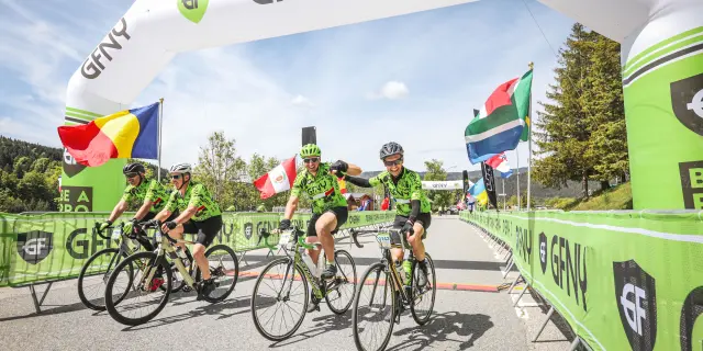 Quatre cyclistes en compétition sur une route, avec des bannières publicitaires colorées en arrière-plan
