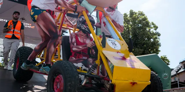 Yellow power tiller operated by a person in a red and blue jumpsuit working in a field