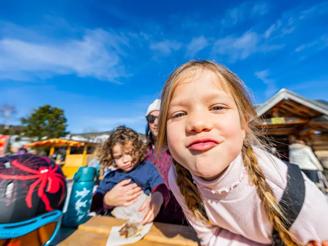 Jeune fille aux cheveux blonds souriante devant des voiliers amarrés dans un port