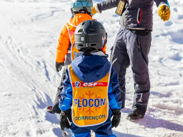 Deux skieurs de fond en compétition, l’un en tenue orange et bleu, l’autre en tenue grise, sur une piste enneigée
