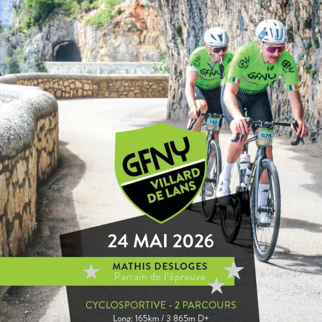 Deux cyclistes en tenue verte et noire en compétition sur une route bordée de rochers et de végétation