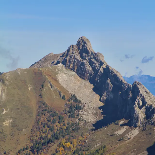 Paesaggio montuoso con rocce dai toni dorati e arancioni sotto un cielo blu chiaro