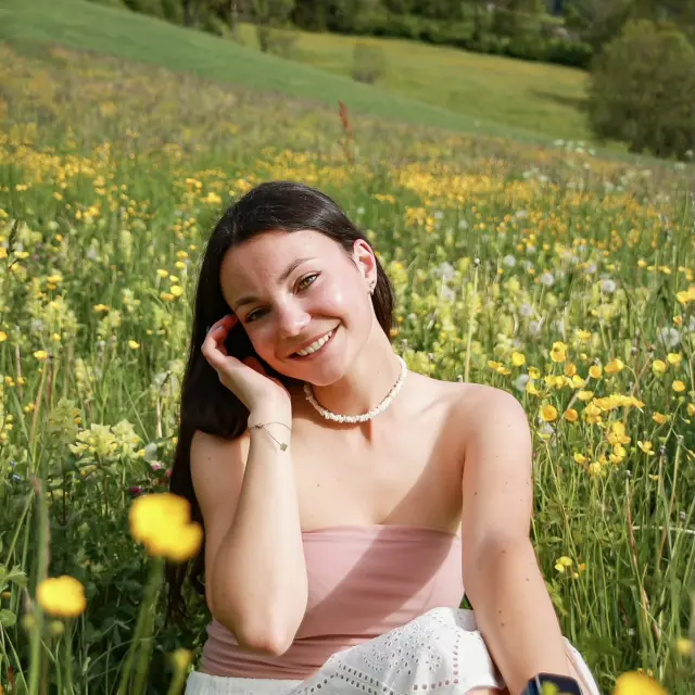 Donna in abito rosa seduta in un campo di fiori gialli