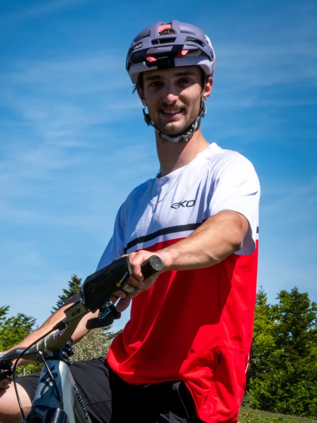 Ciclista in tenuta rossa e bianca su una mountain bike, con casco e occhiali da sole