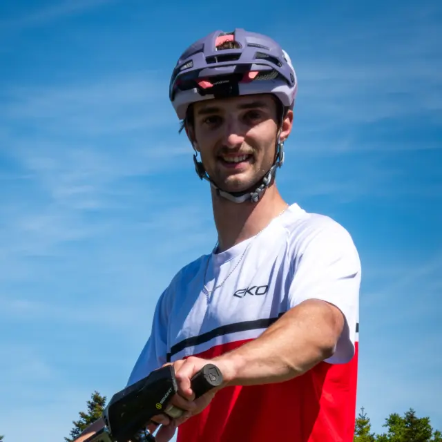 Cycliste en tenue rouge et blanche sur un vélo de montagne, avec un casque et des lunettes de soleil