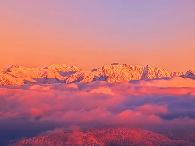 Chaîne de montagnes enneigées avec un ciel aux teintes orangées et violettes