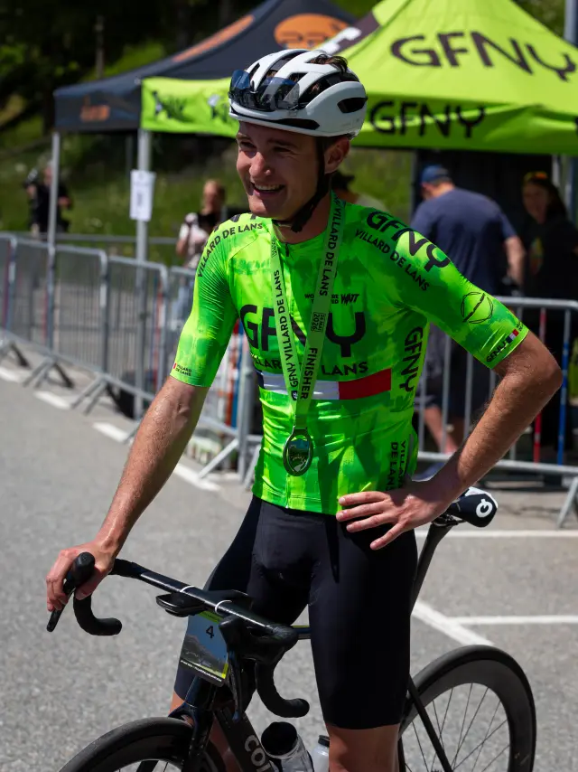 Ciclista con maglia verde fluo e casco con visiera, in competizione su una strada