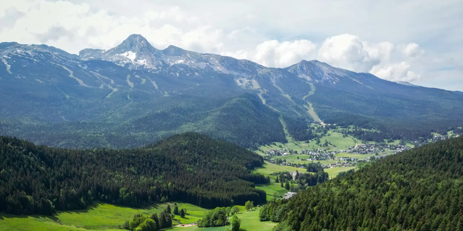 Vue d'une vallée montagneuse avec des prairies en terrasses et des forêts denses