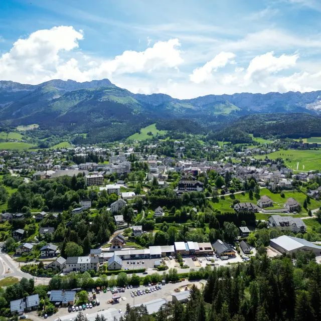 Village de montagne entouré de forêts et de montagnes, avec des maisons dispersées et une route sinueuse