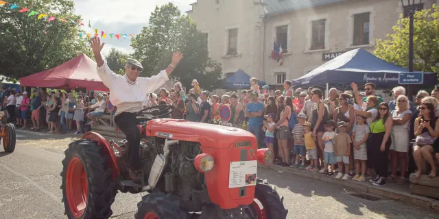 Manège rouge et noir avec nacelles suspendues, entouré de stands et de visiteurs dans une fête de village