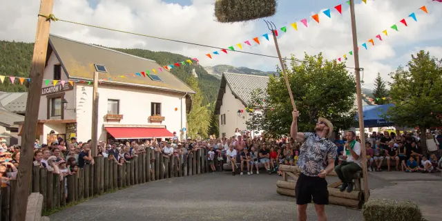 Foule sur un pont piétonnier décoré de drapeaux multicolores, avec des bâtiments en arrière-plan